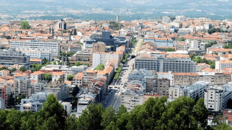 View of Braga from above at Monte Picoto. High view of various buildings most with traditional terracotta style roofing and mountains in the back.